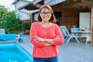 Betreuungskraft im roten Oberteil im Garten mit Pool, 24-Stunden-Pflege
