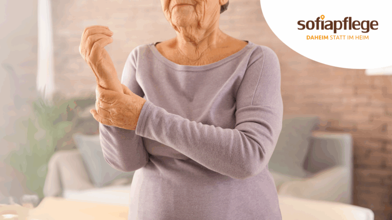 Eine ältere Frau in einem lavendelfarbenen Oberteil hält ihr Handgelenk mit offensichtlichen Beschwerden, möglicherweise aufgrund von Osteoporose. Im Hintergrund ist ein gemütliches Wohnzimmer zu sehen, mit dem Logo "sofiapflege DAHEIM STATT IM HEIM" in der Ecke.