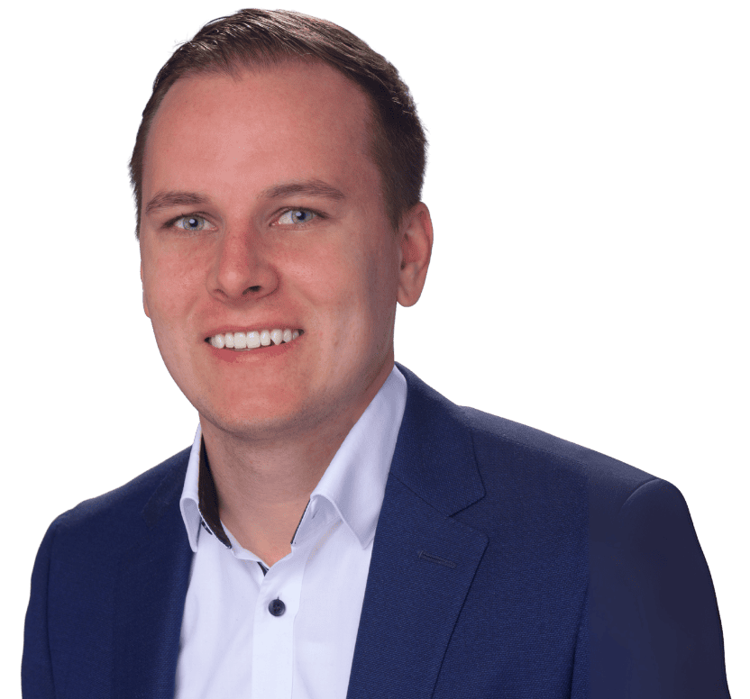 Simon Gsell - Ein Mann mit kurzen hellbraunen Haaren, der eine dunkelblaue Anzugsjacke und ein weißes Hemd trägt, lächelt in einem professionellen Porträt vor einem schlichten Hintergrund in die Kamera.