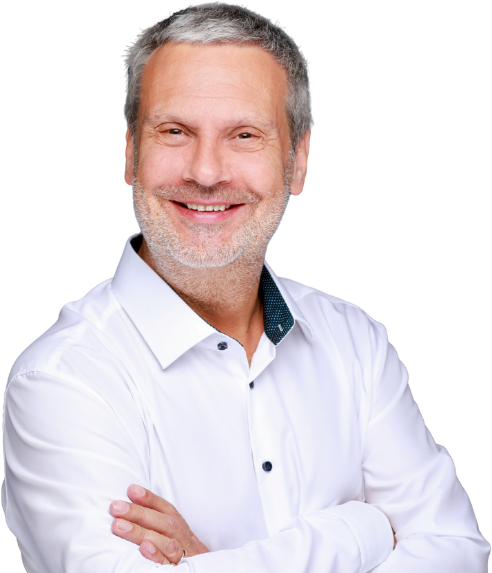 Rene Welter - Ein Mann mittleren Alters mit kurzen grauen Haaren und einem Bart, der selbstbewusst lächelt und die Arme verschränkt, trägt ein weißes Button-up-Hemd vor einem weißen Hintergrund.
