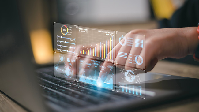 Die Hände einer Person interagieren mit einem Laptop, auf dem futuristische, holografische Datenvisualisierungen - einschließlich Grafiken, Diagramme, globale Statistiken und Stellenangebote - zu sehen sind, die fortschrittliche Datenanalyse und digitale Technologie darstellen.